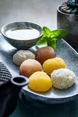 Mochi and green tea served on textured ceramic plate © Yingko