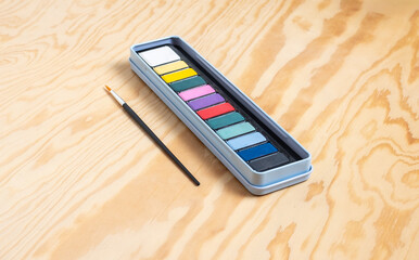 Open watercolor paint set with brush on light wood surface  © Pablo