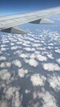 View from the airplane window. Beautiful cloudscape with blue sky. Wonderful panorama above white clouds as seen through window of an plane. Traveling by air concept. 