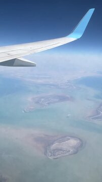 Airplane wing view over sea, with clouds and a blue sky. Travel and aviation concept for business and tourism use.
