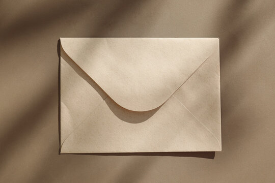 Minimal Kraft Paper Envelope Mockup on Beige Textured Table Background, in Sunlight, Natural Shadows. Blank Eco Stationery Template for Branding, Mailing, Wedding Invitation. Business Identity