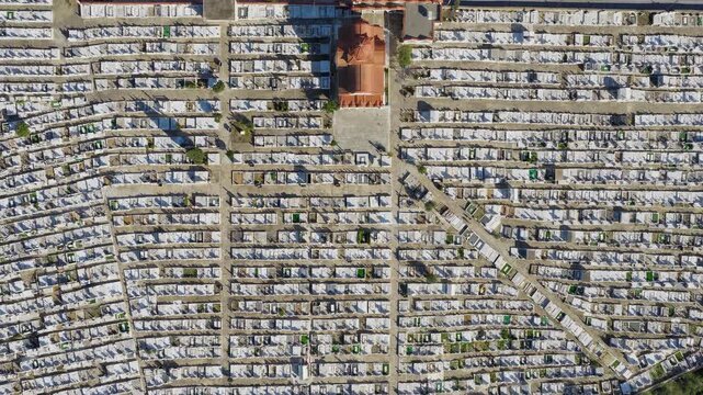 Overhead top down drone footage of Pyrgos cemetery, Ilia, Greece. Graves, monuments and pathways visible. Sunny clear day