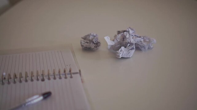 Crumpled paper balls are thrown across a desk during a brainstorming session, illustrating frustration, mistakes, and the creative process at work.