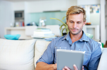 Fototapeta premium Man, internet and remote work in home with tablet, research trend and AI software for logo design. Freelancer, person or graphic designer on sofa with tech, planning or innovation for digital project
