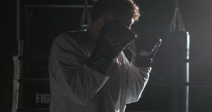 Young boxer practicing punches with a coach during an intense mitt training session in a boxing gym. Focused athlete improving striking technique, speed, defense and coordination under professional