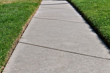 Obraz premium The Concrete Sidewalk Leading Through Green Lawns On A Sunny Day