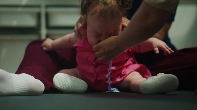 Close up of caregivers comforting an infant with a pacifier during a developmental therapy session,