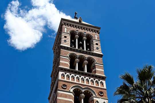 Church bell tower of St. Paul's Within the Walls. arched windows, stone columns. Gothic Revival style tower. the first Protestant church in Rome, Italy. lush palm tree. blue sky. architecture, travel