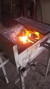 Industrial blacksmith forge blowing wind with intense hot orange sparks flying.