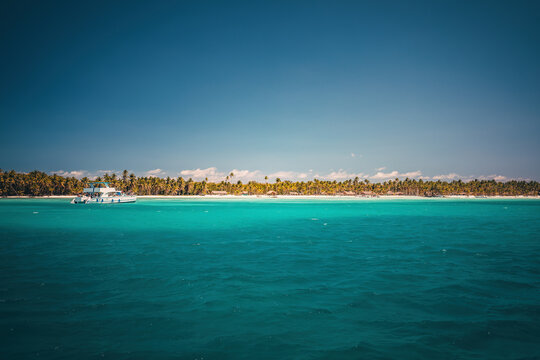 White cruise boat in turquoise sea water near Saona Island tropical beach