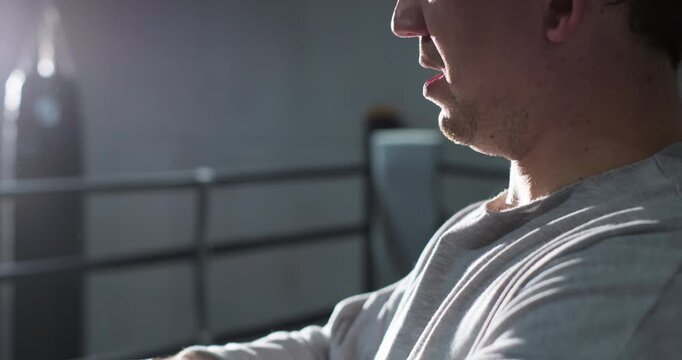 Close-up portrait of a focused boxer preparing hand wraps before a boxing workout in the gym. Concentrated athlete getting ready for training, emphasizing discipline, preparation and dedication to