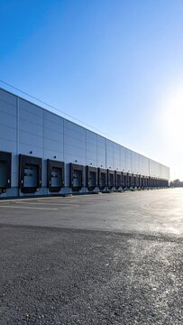 Long modern warehouse with many loading docks under a clear sky