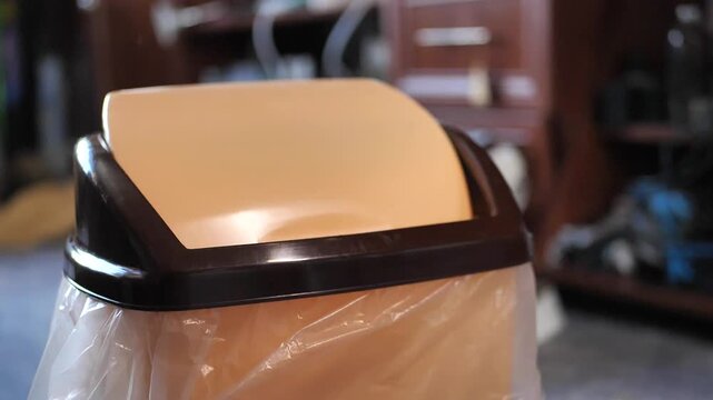 Close-up of a banana peel falling into a kitchen trash can, slow motion. Food waste disposal in household containers. Recycling and waste management concept.
