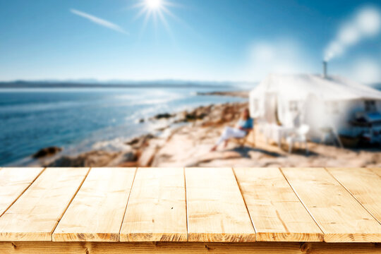 Lake camping with mountain view and wooden table with copy space &ndash; outdoor summer adventure concept.