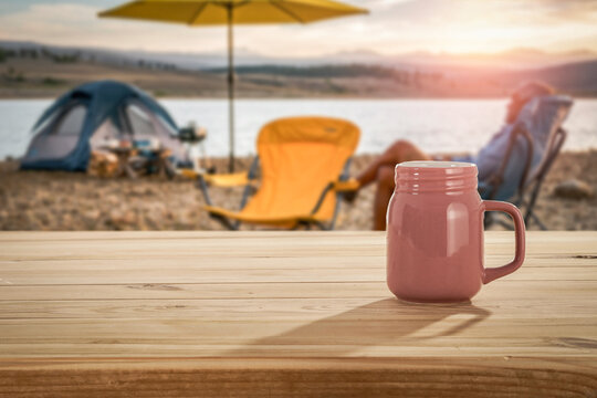 Lake camping with mountain view and wooden table with copy space &ndash; outdoor summer adventure concept.