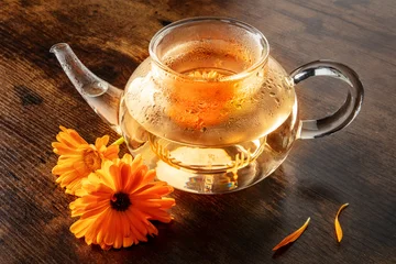 Calendula Tea. Vibrant orange marigold flowers infusing in a clear glass teapot © laplateresca
