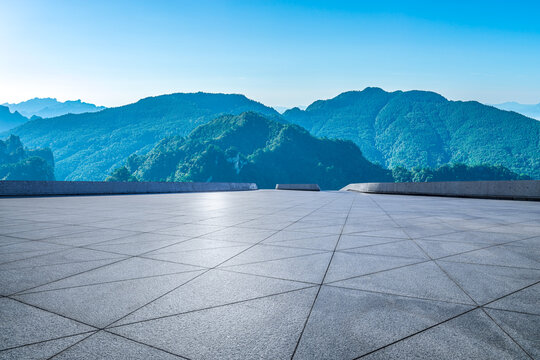 Empty plaza floor and scenic mountain range under a blue sky