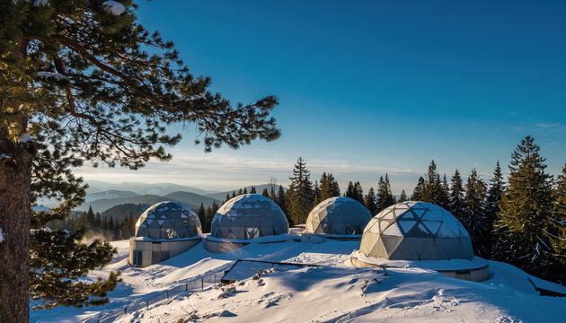 Snowy mountain winter landscape featuring geodesic domes against a backdrop of a clear blue sky