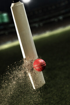 Cricket bat striking red leather ball with exploding dirt on stadium field. Concept of cricket competition, powerful impact and professional sports advertising.