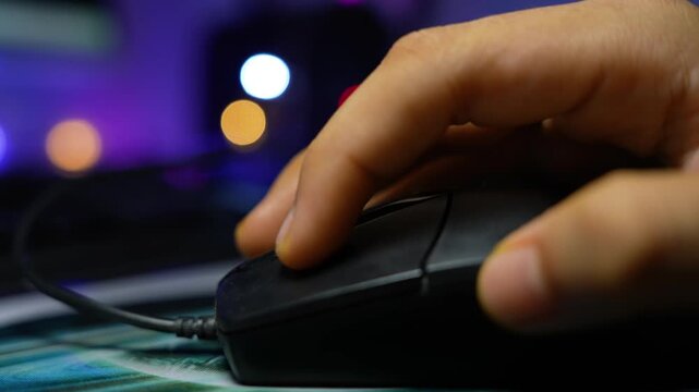 Hand using computer mouse with blurred lights, Close-up of a hand using a computer mouse with colorful blurred lights in the background
