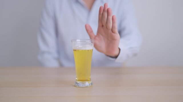 man making stop hand gesture to refuse a glass of Beer, Healthy man say no to alcohol drink, stop alcoholism and addiction concept. Responsible man reject a drink before driving and quit booze