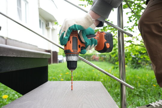 Worker drilling outdoor composite stair step with cordless screwdriver