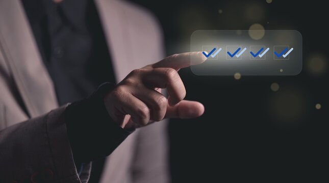 Hand touches virtual screen, activating checkmarks. This action symbolizes digital completion, agreement, and efficiency for business tasks in a modern technological environment