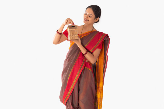 Portrait of a Maharashtrian woman putting coin into money box