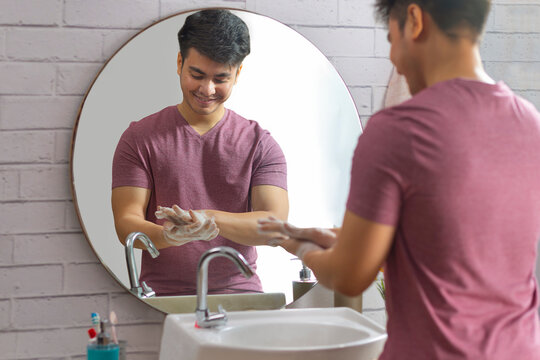Portrait of young man washing his hands in bathroom