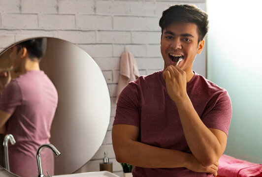 Young man brushing his teeth in bathroom
