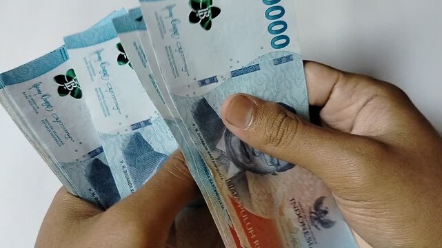 A close-up of a person counting Indonesian 50,000 rupiah banknotes by hand, representing personal finance, cash transactions, savings, budgeting, banking, business payments, and the Indonesian economy