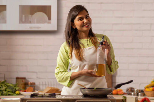 Portrait of cheerful woman cooking in kitchen