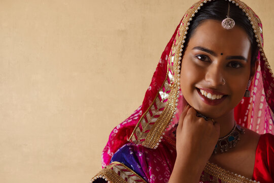 Close-up portrait of a cheerful Rajasthani young woman against plain background