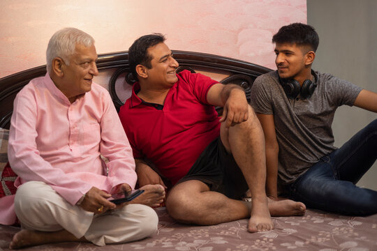 Multi generation Indian family sitting on bed in bedroom
