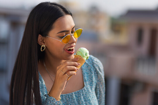 Portrait of young woman eating ice cream in cone