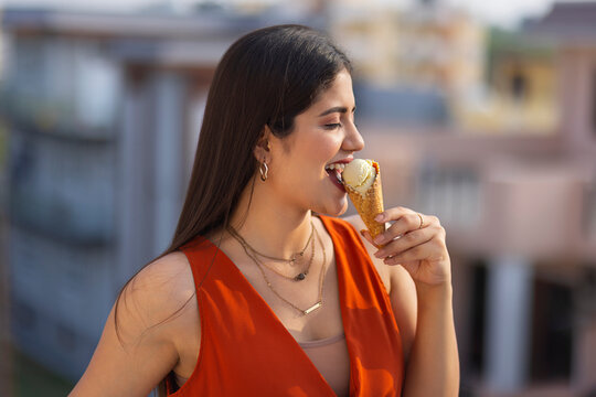 Portrait of young woman eating ice cream in cone