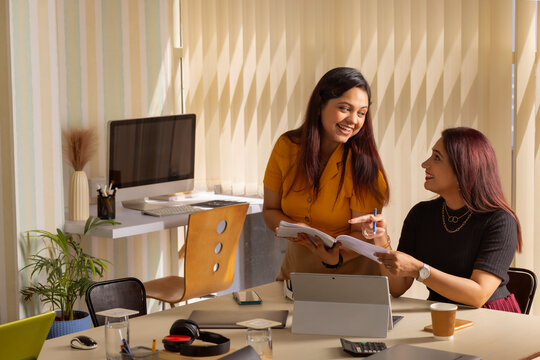Two businesswomen discussing a project at office workstation