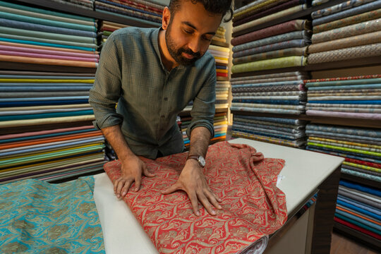 Man showing a piece of patterned fabric in a clothing store 