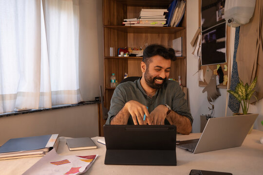 A male designer using laptop and tablet in his studio