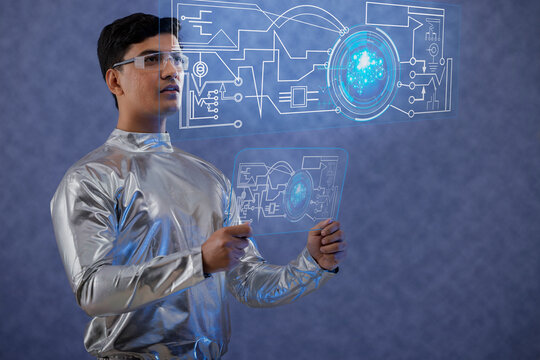 A man wearing silver,futuristic  clothes holding digital tablet,and looking at a virtual screen. A future technology concept