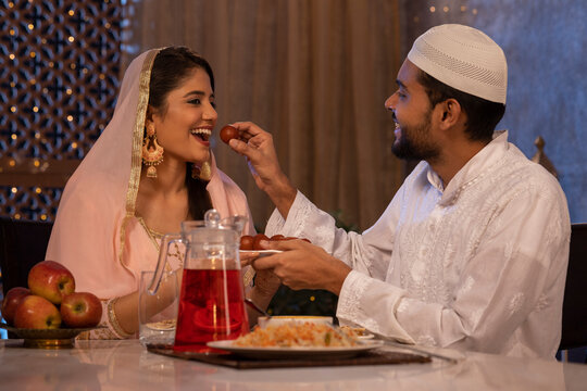 Muslim man feeding a gulab jamun to his wife