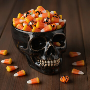 halloween themed skull bowl filled with candy corn and chocolate on wooden table spooky decoration
