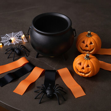 halloween decorations with cauldron, pumpkins, and spider on table concept of spooky holiday setup