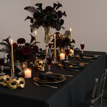 elegant halloween table setting with black and gold decor, candles, and skulls creating a spooky ambiance