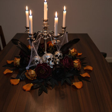spooky candlelit dinner setting with skulls and roses, creating a halloween atmosphere