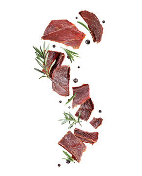 Dried pieces of beef with rosemary and allspice in the air isolated on a white background