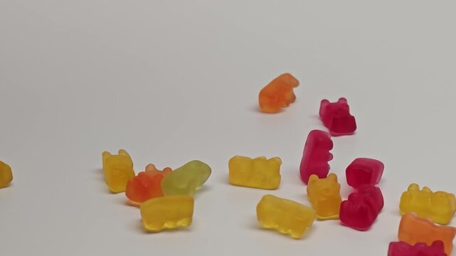 Marmalade bears fall slowly and bounce around on a white surface