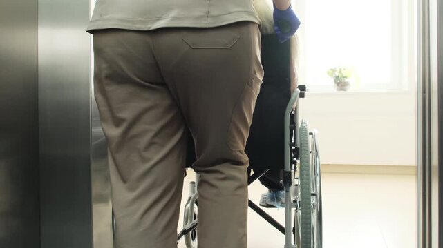 Doctor transports patient through medical center toward diagnostic offices. Physician escorts patient toward rehabilitation area. Slow motion