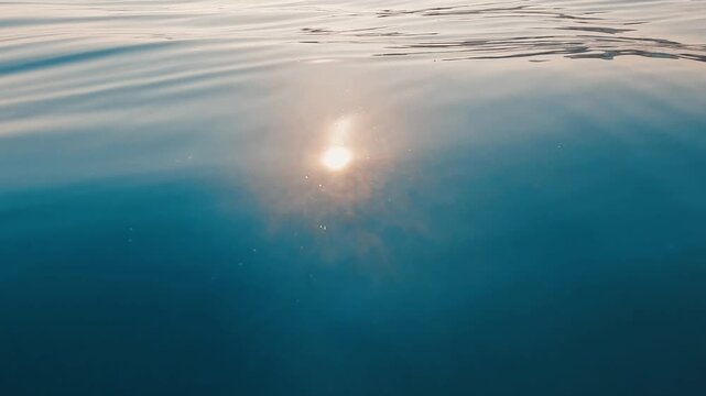 V&iacute;deo de la superficie del mar en calma con reflejo solar y ondulaciones suaves.