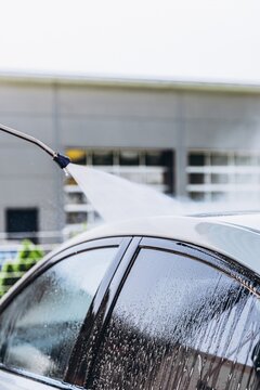 Pressure washer cleaning a car at a self service car wash. Vehicle care and auto detailing concept.